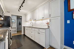 Kitchen featuring white cabinetry, dark stone counters, sink, and decorative backsplash