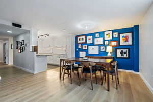 Dining space featuring rail lighting, sink, and light wood-type flooring