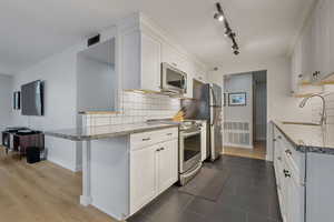 Kitchen with appliances with stainless steel finishes, sink, and white cabinets