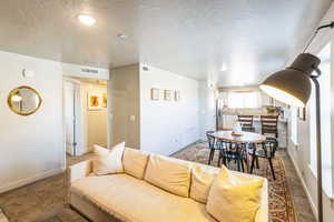 Living room with carpet flooring and a textured ceiling