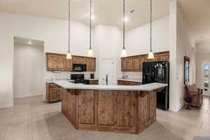 Kitchen with pendant lighting, a center island, high vaulted ceiling, and black appliances