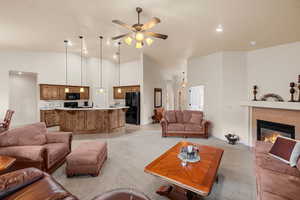 Living room featuring light carpet, a fireplace, high vaulted ceiling, and ceiling fan