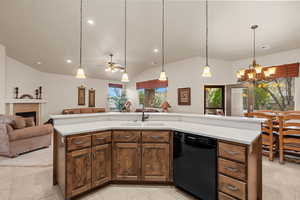 Kitchen with decorative light fixtures, dishwasher, sink, and a center island with sink