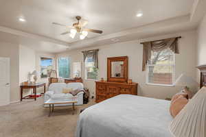 Carpeted bedroom featuring a tray ceiling, a textured ceiling, and ceiling fan