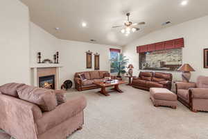 Living room featuring carpet, a healthy amount of sunlight, lofted ceiling, and a fireplace