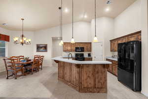 Kitchen featuring pendant lighting, high vaulted ceiling, a center island with sink, and black appliances