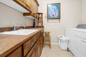 Washroom featuring sink, cabinets, independent washer and dryer, and light tile patterned flooring