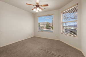 Carpeted spare room featuring ceiling fan