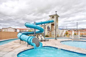 View of swimming pool with a water slide, a playground, and a patio area