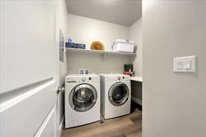 Clothes washing area featuring washing machine and dryer and light wood-type flooring