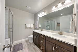 Bathroom with hardwood / wood-style flooring, vanity, toilet, and walk in shower