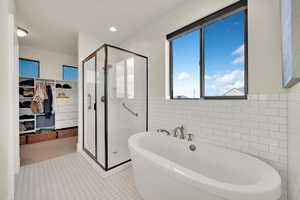 En-suite bathroom with shower and separate soaking bathtub, subway tile walls and access to custom walk-in closet.