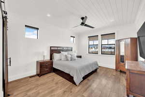 Primary bedroom featuring ornamental  wood molding, ceiling fan, and barn door access to the en-suite bathroom & walk-in closet.