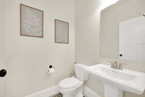 Half bathroom with pedestal sink and toilet. This is just off of the entry room and near the laundry.