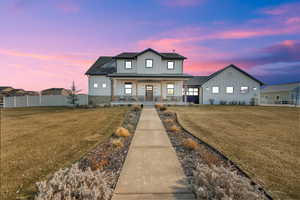 View of  the front featuring the corner yard and covered porch, breezeway and attached garage.