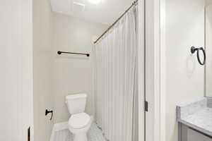 Full bathroom with tile patterned floors, vanity, toilet and shower/tub combo.