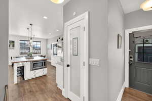 Kitchen with pendant lighting, stainless steel microwave, butcher block countertops, white cabinetry, and pantry door. To the right you can note the other access door from the breezeway.