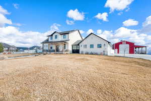 View of the front of the home with a; porch, a 3 car garage, the barn with attached carport and additional parking.