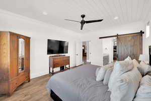 Primary bedroom featuring ornamental  wood molding, ceiling fan, and barn door access to the en-suite bathroom & walk-in closet.