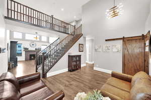 Front entry room with composite hardwood LVP flooring, expansive ceiling heights, upstairs walkway and neutral paint.