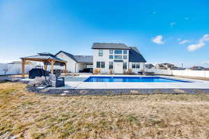 Back of property featuring a 40x20 foot heated vinyl sports pool, a gazebo, a portion of the lawn, and a patio area. This space is fenced in.