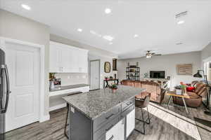 Kitchen with a kitchen island, light stone countertops, a breakfast bar area, and white cabinets