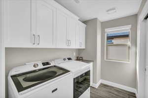 Washroom featuring cabinets, washing machine and dryer, and hardwood / wood-style floors