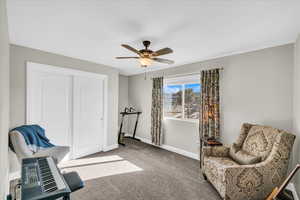 Sitting room featuring ceiling fan and carpet flooring