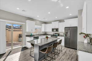 Kitchen featuring dark stone countertops, stainless steel appliances, a breakfast bar, and white cabinets