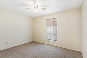 Carpeted empty room featuring ceiling fan and a textured ceiling