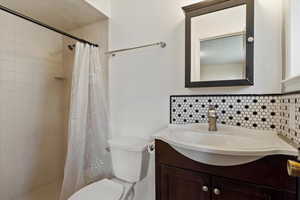 Bathroom with vanity, curtained shower, backsplash, and toilet