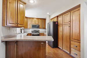 Kitchen with light hardwood / wood-style floors, stainless steel appliances, kitchen peninsula, and sink