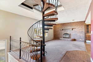 Staircase featuring brick wall, carpet flooring, and a textured ceiling