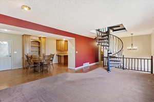 Living room featuring a textured ceiling, carpet floors, and a chandelier