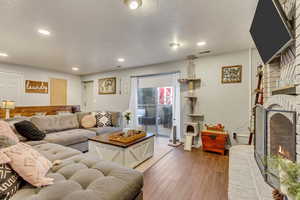 Living room featuring a textured ceiling, a brick fireplace, and light hardwood / wood-style flooring