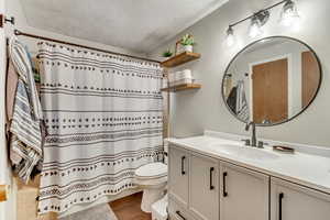 Bathroom with hardwood / wood-style flooring, vanity, a textured ceiling, and toilet