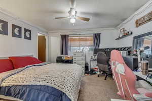 Carpeted bedroom featuring ceiling fan and a textured ceiling