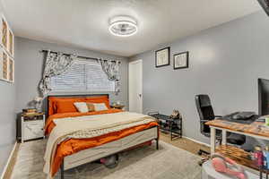 Bedroom featuring light carpet and a textured ceiling