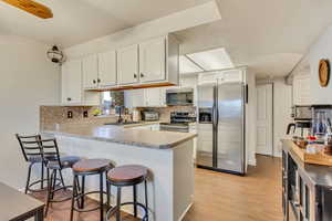 Kitchen featuring white cabinetry, sink, stainless steel appliances, and kitchen peninsula