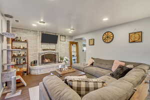 Living room featuring hardwood / wood-style flooring, brick wall, and a brick fireplace