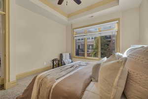 Bedroom featuring a raised ceiling, crown molding, carpet, and ceiling fan