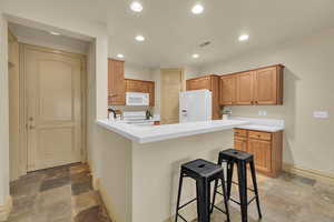 Kitchen featuring white appliances, a kitchen breakfast bar, and kitchen peninsula