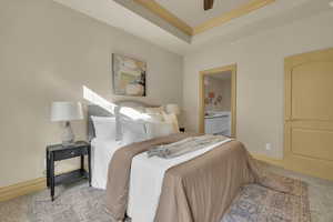 Bedroom featuring crown molding, light carpet, connected bathroom, and a tray ceiling