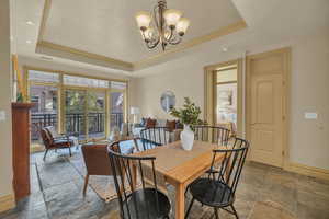 Dining space with an inviting chandelier, a tray ceiling, and ornamental molding