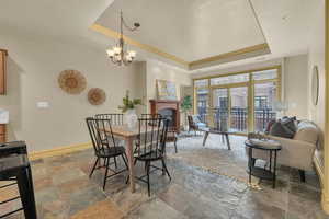 Dining area featuring a raised ceiling, ornamental molding, and a notable chandelier