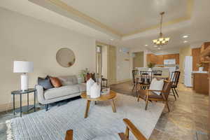 Living room featuring a notable chandelier, crown molding, and a raised ceiling