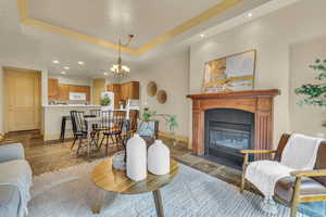 Living room featuring a raised ceiling, crown molding, and an inviting chandelier