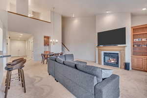 Living room featuring light colored carpet, a high ceiling, and a notable chandelier