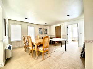 Carpeted dining room with a baseboard heating unit, radiator heating unit, and a textured ceiling