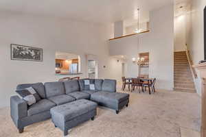 Carpeted living room featuring ceiling fan with notable chandelier